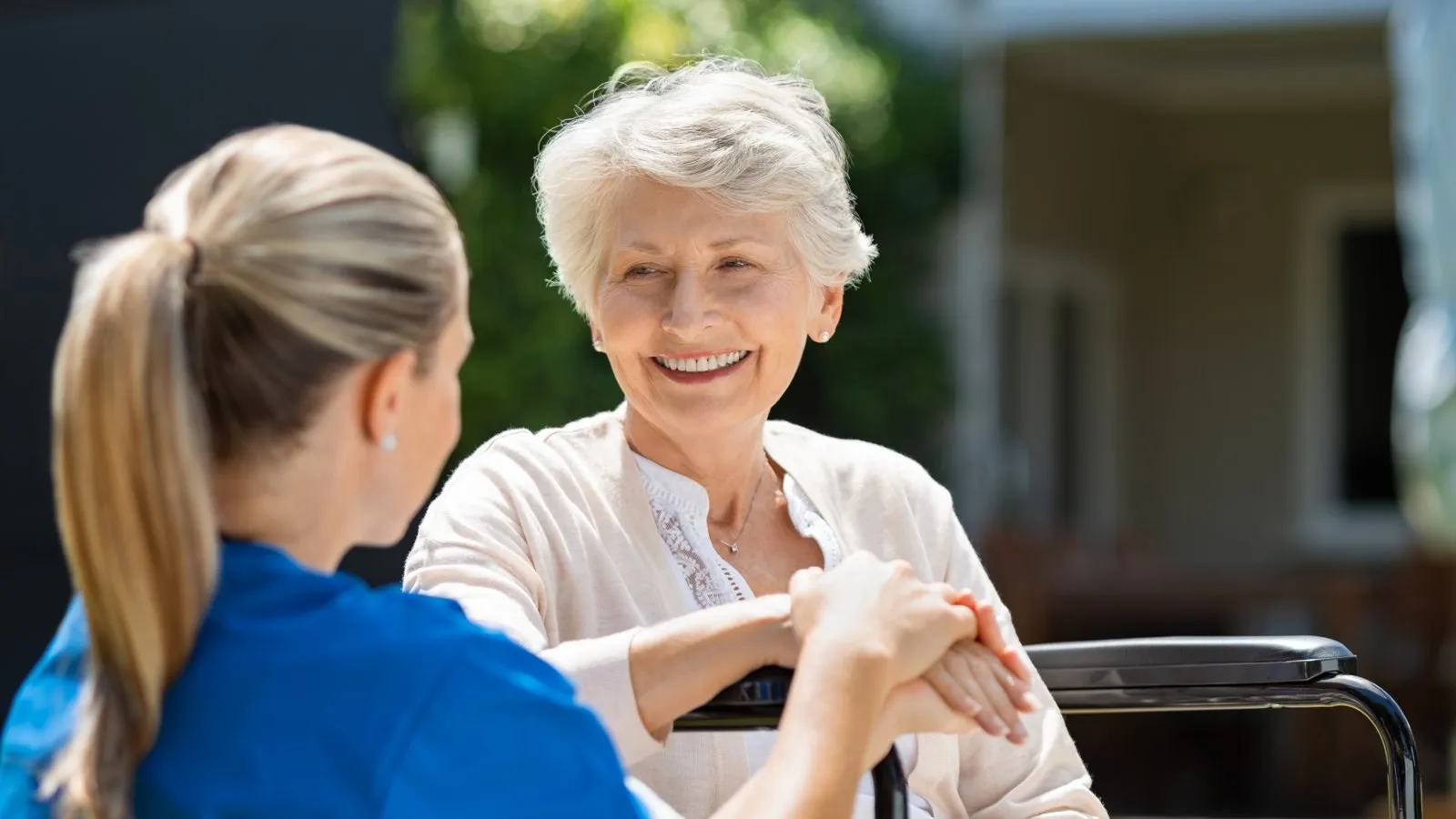A nurse sitting with a smiling older resident in a garden