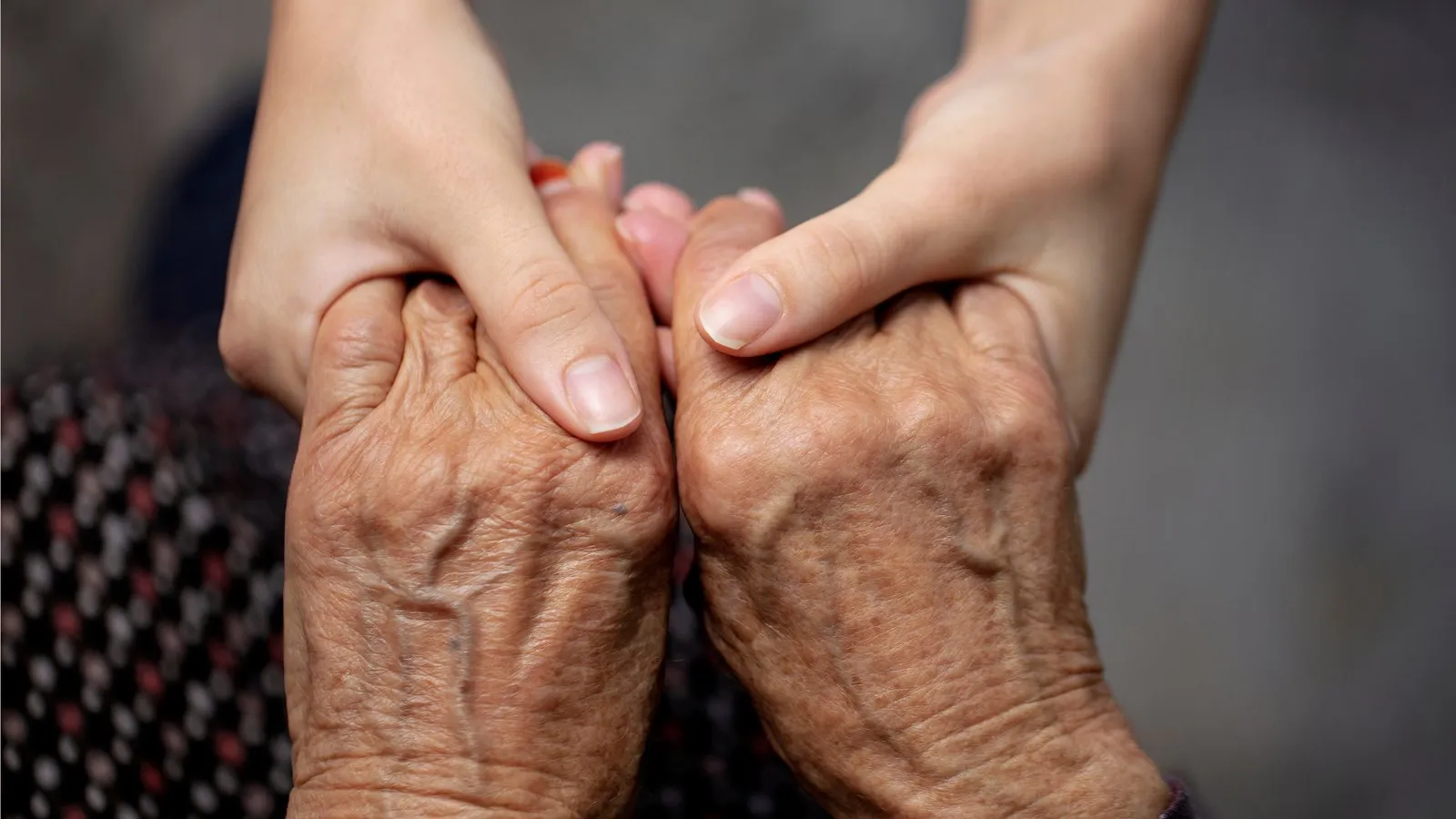 A carer gently holding an older person's hands