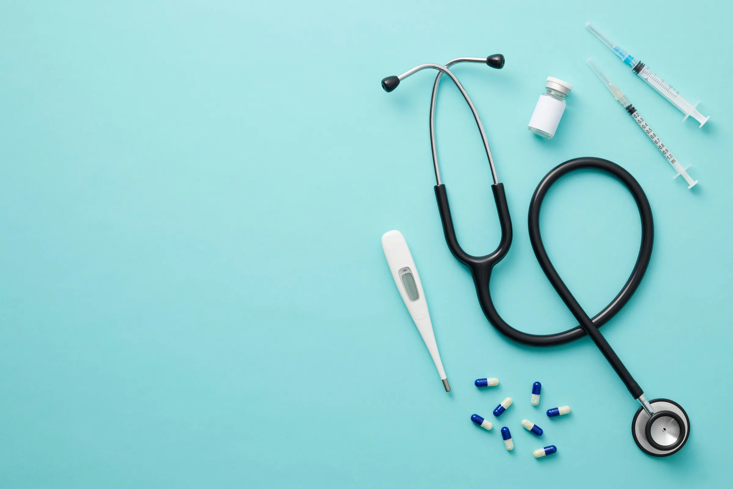 Stethoscope, thermometer and medications arranged on a table